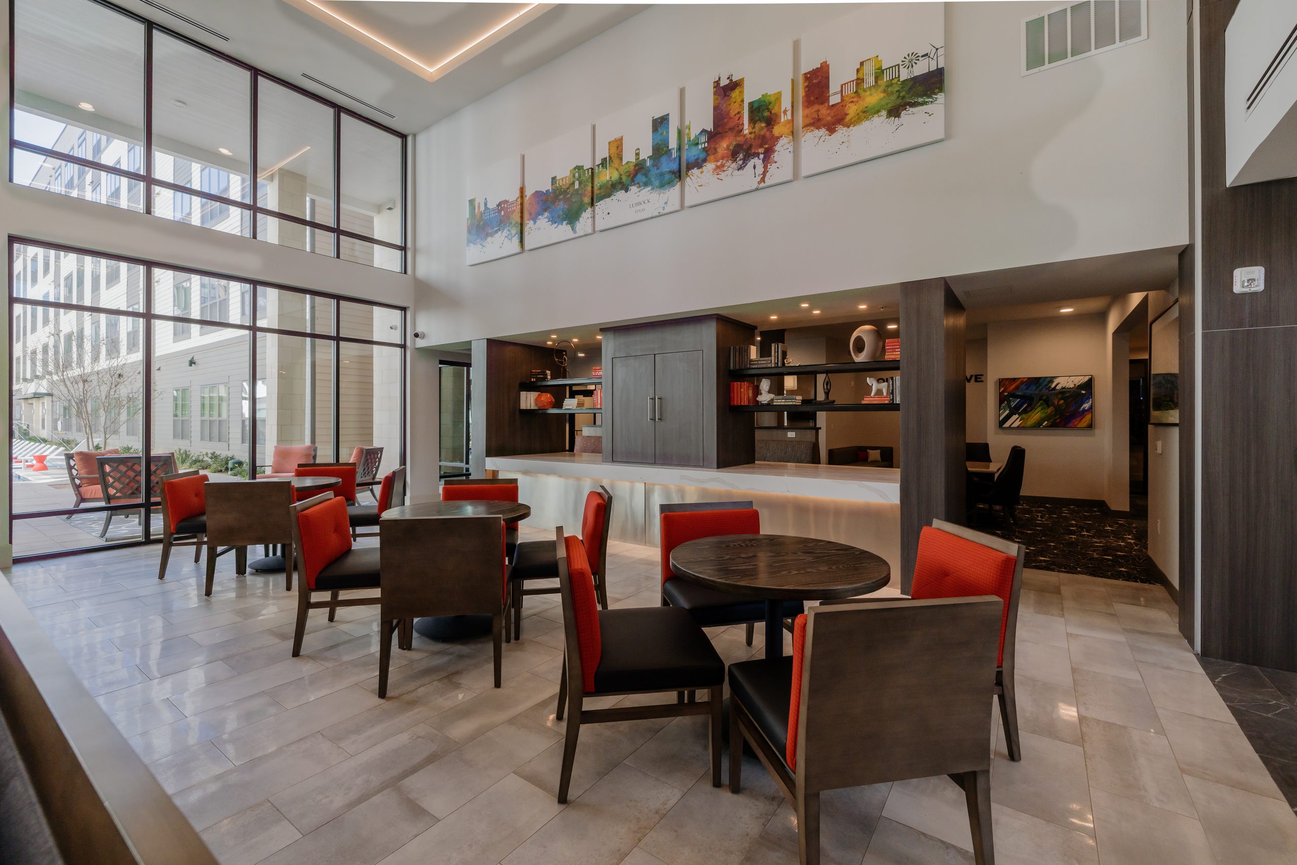 Clubhouse dining tables and lounge seating under a double-height window wall