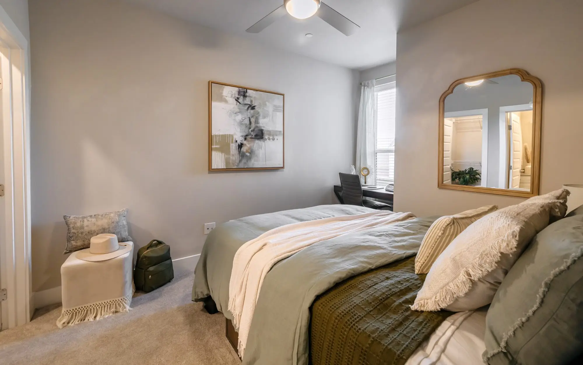 Bedroom dressed in layered bedding beside a full-length mirror